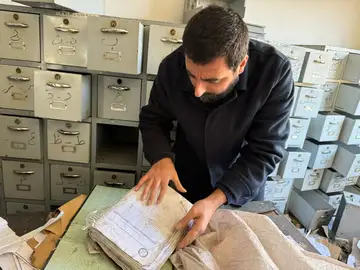 Amer Matar examining detention records in a room filled with filing cabinets in Syria