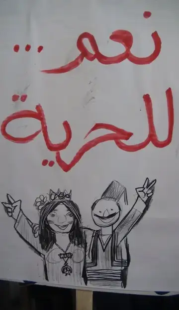 Banner reading We Want Freedom with drawings by Youssef Abdelke