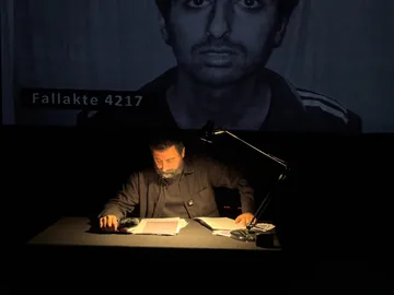 Amer Matar reading from Dossier 4217 on stage in Hanover