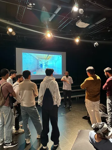 Amer Matar guiding visitors through the Sednaya exhibition in Hanover beside a projected 3D prison reconstruction