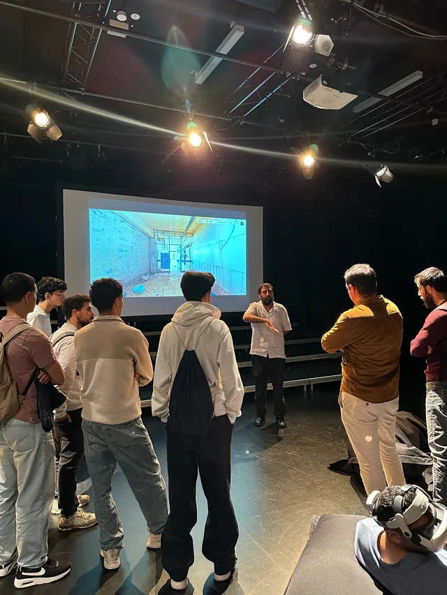 Amer Matar guiding visitors through the Sednaya exhibition in Hanover beside a projected 3D prison reconstruction