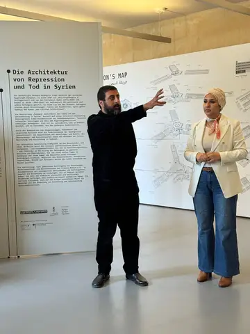 Amer Matar guiding visitors through the Sednaya exhibition beside the prison map