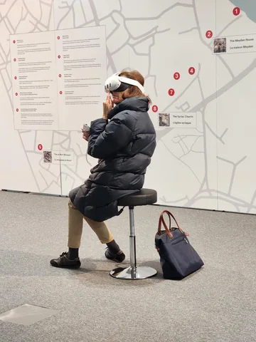 A visitor using virtual reality in front of the Old Mosul map at the Three Walls exhibition, UNESCO, Paris